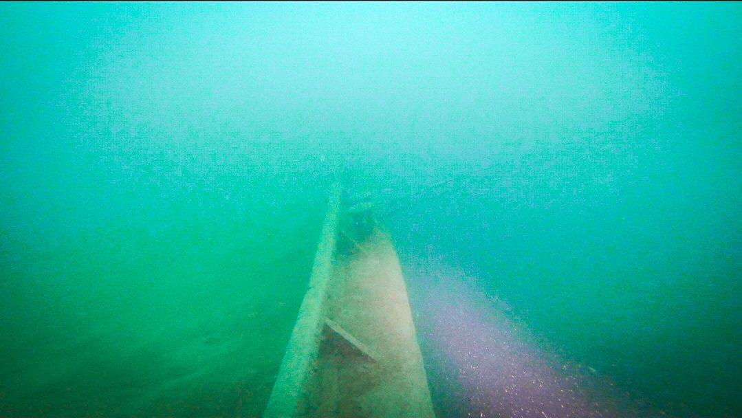 Rumpf eines Wracks in grünem Seewasser